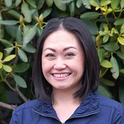 Hansen Dentistry Staff Member Ann Smiling In Front Of Shrub
