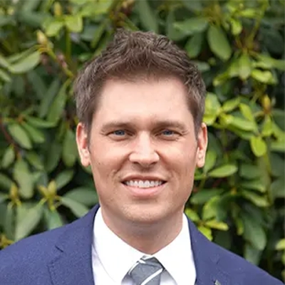 Dentist Stephen Hansen Smiling In Front Of Shrub