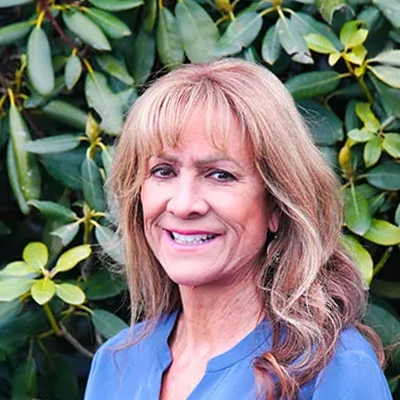 Hansen Dentistry Staff Member Tammie Smiling In Front Of Shrub